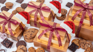 Stacks of Famous 4th St. Gift Towers with santa hats, chocolate chip cookies, brownies, pretzels, and mini oatmeal raisin cookies.
